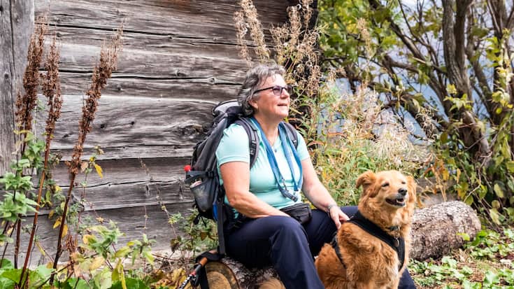 Christine Nydegger und Mischlingshündin Tapas gönnen sich eine Pause auf einem Baumstamm