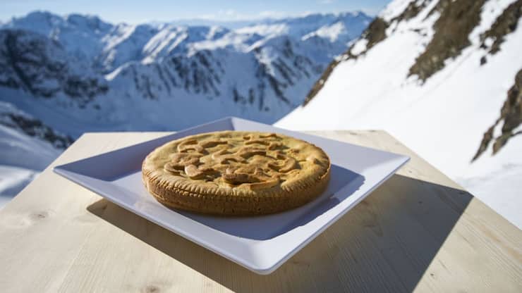 Medelser Nusstorte mit Bergpanorama im Hintergrund
