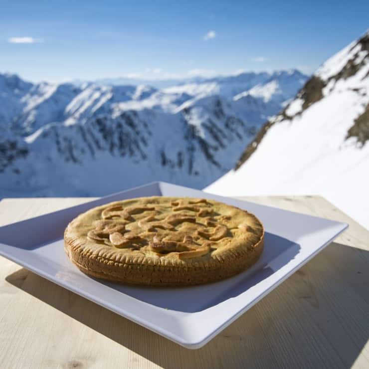Medelser Nusstorte mit Bergpanorama im Hintergrund