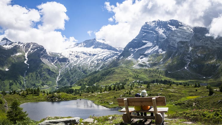 Besonders für Familien ist die Bergalpeam Simplon ein ideales Wandergebiet. Die beiden jungen Wanderer geniessen die Pause auf einem Bänkli am Weg.Über dem Hopschusee erhebt sich der Monte Leone, rechts davon zeigt sich das Hübschhorn.