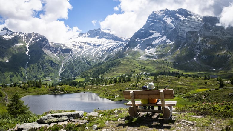 Besonders für Familien ist die Bergalpeam Simplon ein ideales Wandergebiet. Die beiden jungen Wanderer geniessen die Pause auf einem Bänkli am Weg.Über dem Hopschusee erhebt sich der Monte Leone, rechts davon zeigt sich das Hübschhorn.