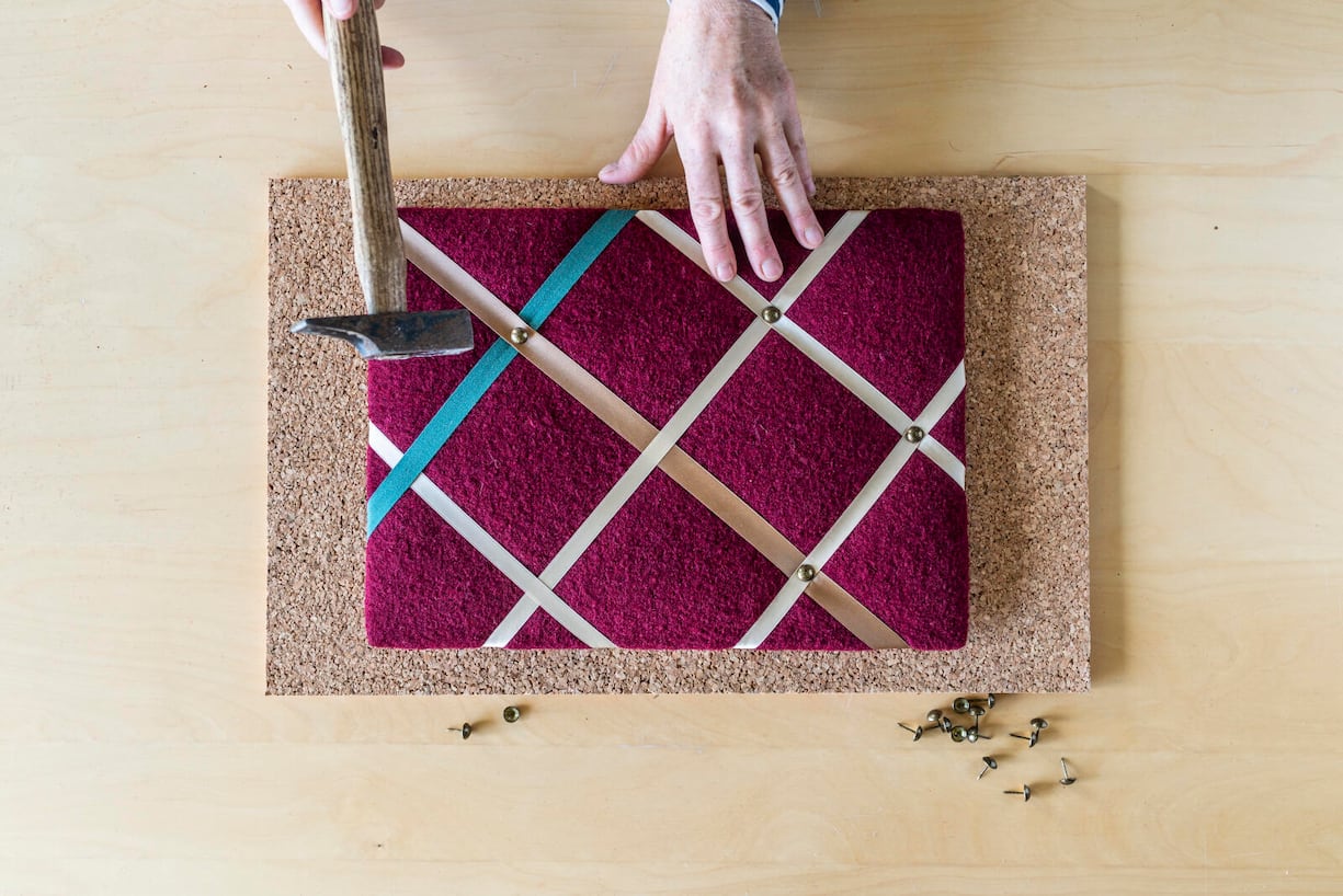 Bunte Bänder werden mit Hammer kreuzweise auf einem Rahmen fixiert