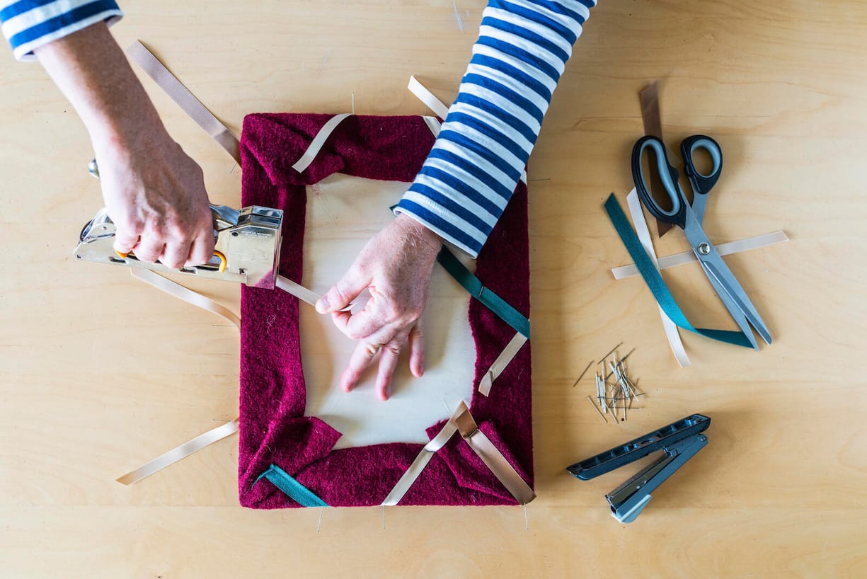 Bunte Bänder werden an einen Rahmen angeheftet