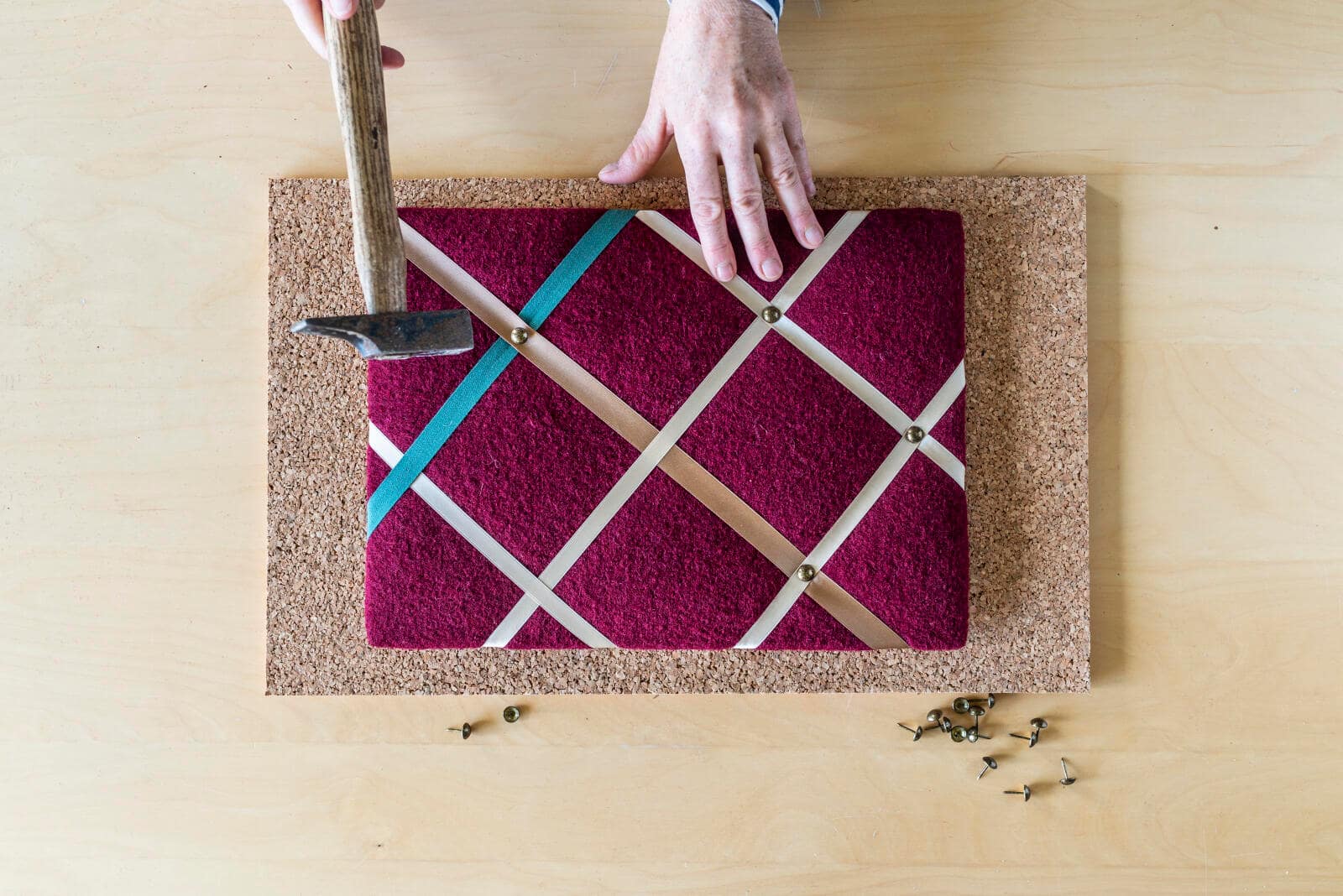 Bunte Bänder werden mit Hammer kreuzweise auf einem Rahmen fixiert