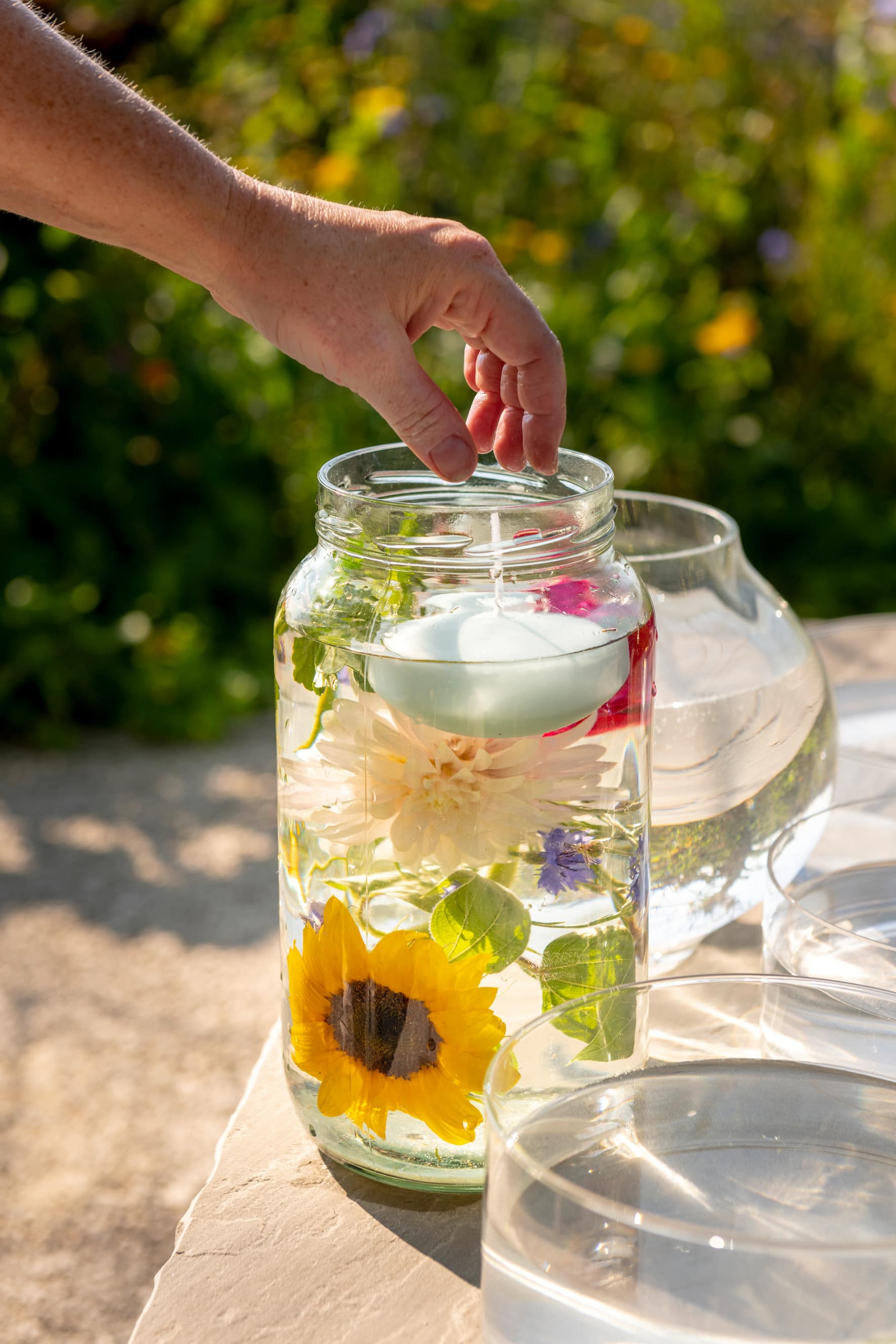 Hohes Glas mit Blumen und Schwimmkerzen
